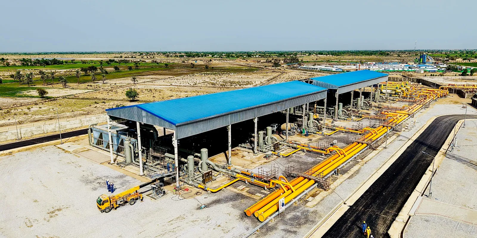 Aerial view of a gas compression station with compressor packages and yellow gas headers